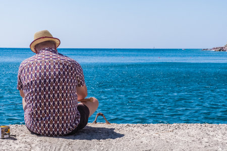 Fisherman on a pier with blue water in Santorini, Greeceの写真素材