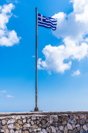 The blue and white flag of Greece with a clear sky with clouds on a sunny dayの写真素材