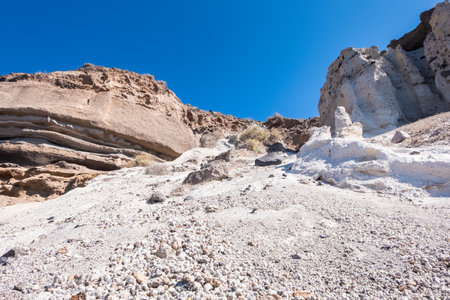 The coast of the island santorini is composed of rocky walls and sandの写真素材