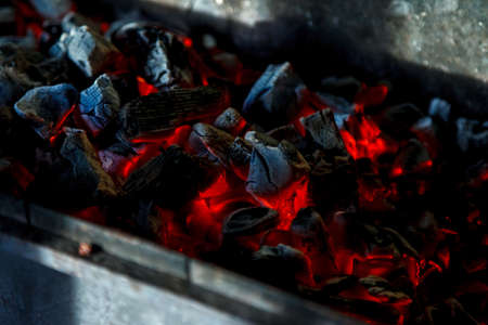 Hot coals. Coal combustion. Close-up of red-hot coals blazing on grill. Close up. View from top. Dark background for creative process. Barbecue process. Home cookingの写真素材