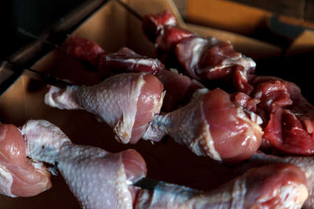 Raw chicken. Chicken meat on skewers for cooking over an open fire. Chicken legs on dark background. Fresh chicken meat for cutting. Bush Legs. View from top. Delicious meat close upの写真素材