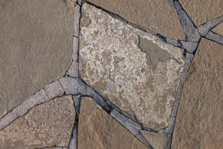Textured stone background with cement elements. Fragment of wall or sidewalk made of rubble. Design space made of vintage chipped stone. Space for your label, signature, or logoの写真素材