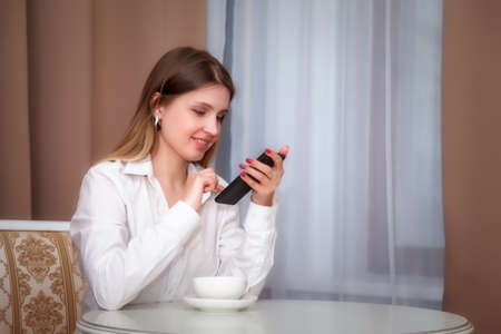 Girl of Slavic appearance in bar, cafe or restaurant with white Cup. Female shows emotion. Young...