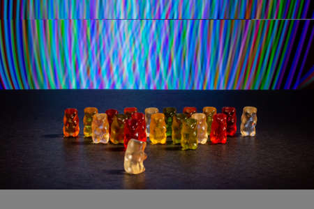 a line of multi-colored bears made of gelatin against a background of lightの写真素材