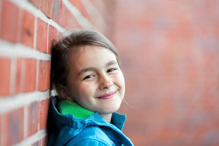 Portrait of  happy little cute girl next to Brick Wallの写真素材