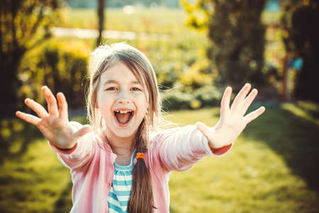 happy little girl with hands up in summer park  Retro filter photoの写真素材