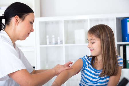 little girl receiving injection  with a smile.の写真素材