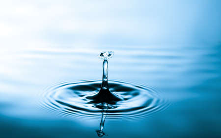 Splash of water crown on blue.Droplet falling in blue waterの写真素材