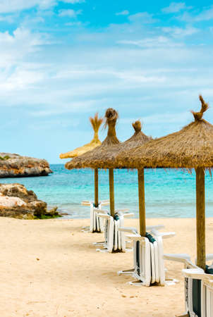 Straw parasols and beds on the sandy beach.の写真素材