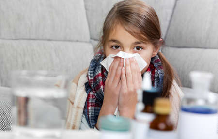 Little girl  sneezing In to tissue.Little girl cleaning noseの写真素材
