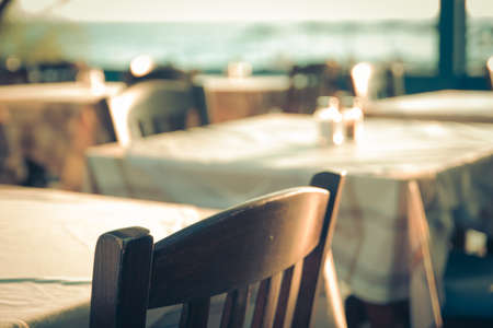 traditional greek outdoor restaurant on terrace overlooking Mediterranean sea (Greece ). empty table at an street sea restaurant. toned image.の写真素材