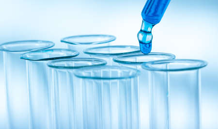 Pipette adding fluid to one of several test tubes .medical glassware