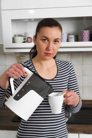 Pretty girl preparing tea in the kitchenの写真素材