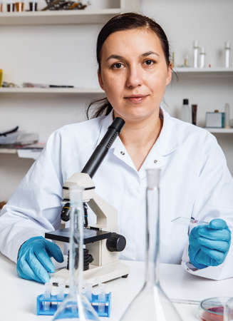 Woman working with a microscope in a lab.Toning imageの写真素材