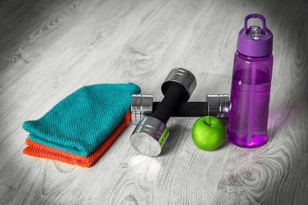 Fitness equipment. Healthy food. Water,apple on wooden background