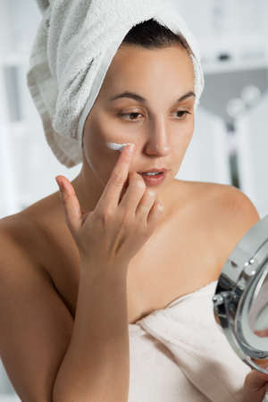 Young woman with cosmetic cream on a clean fresh face. Skin care concept.の写真素材