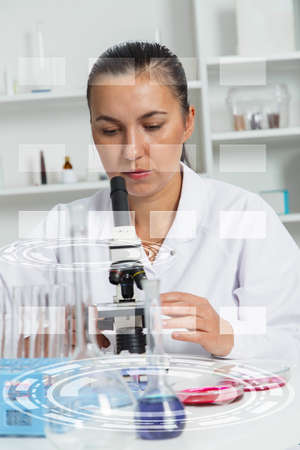 Young Female Scientist Analyzing Sample In Laboratory.laboratory assistant analyzing a sample.