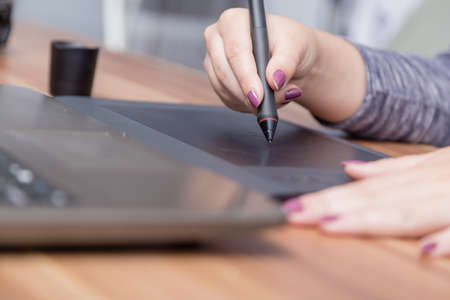 Hands of female designer in office working with digital graphic tablet . Creative people or advertising business concept.の写真素材