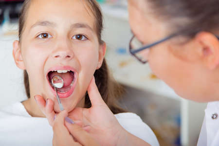 Close-up of little girl opening his mouth wide during treating her teeth by the dentistの写真素材