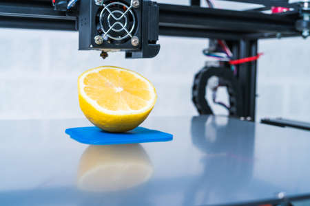Ripe slice of yellow lemon citrus fruit . 3d printer of the device during the processe.