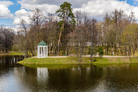 Spring view of the city park and pond, which reflects the blue sky with cloudsの写真素材