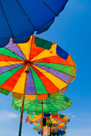 Old multicolored colorful umbrellas with wear tracks on blue sky background.の写真素材