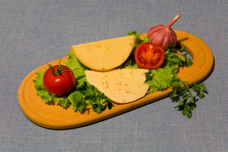 Vegetables and cheese beautifully lie on a cutting board.
