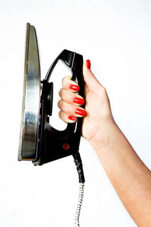 Old vintage iron in a graceful female hand with red nails on a white background.の写真素材