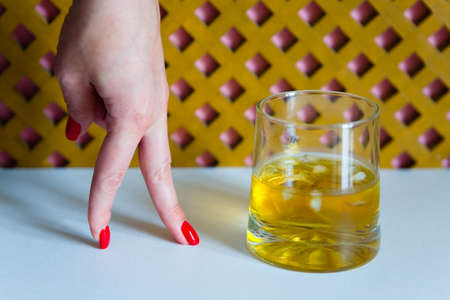 Time of whiskey. A glass of whiskey and a woman's hand with a beautiful manicure.の写真素材