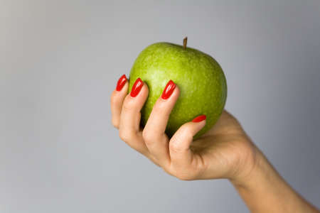 A green apple in a graceful female hand. Background - gradient.の写真素材