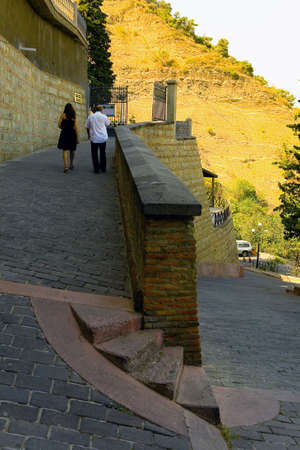 Tbilisi, Georgia, August 27, 2017: A man and a woman are climbing up a stone path.のeditorial素材