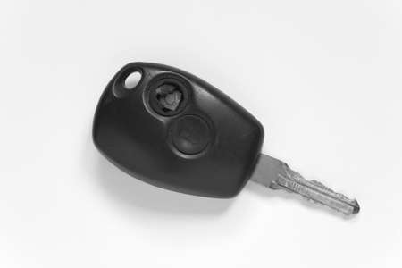 Old ignition key with a broken button. On a sheet of white paper.