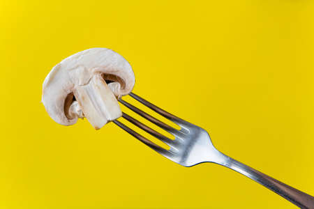 Half a champignon on a fork. On a yellow background.の写真素材