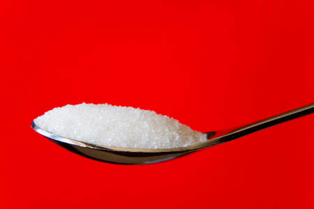 Sugar sand on a spoon on a red background. Close-up.の写真素材