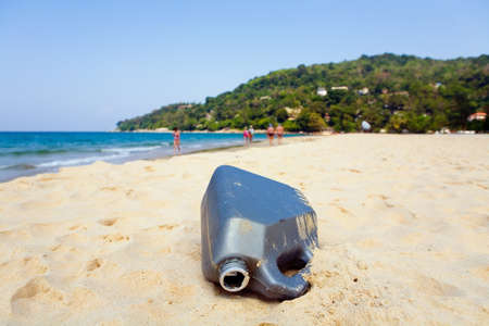 An empty plastic canister is lying on the sand of the resort beach. Pollution of environment.