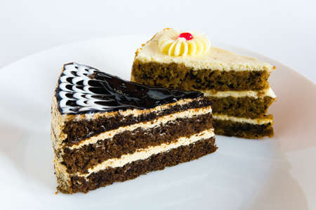Two pieces of cake lie on a white plate. On a light background.