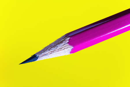 Cheap sharp sharpened pencil on a yellow background. Closeup.の写真素材