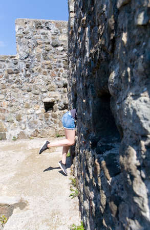 Beautiful slender female feet next to a stone wall. Part of the body.