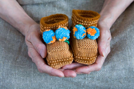 Booties in the hands of an elderly woman. Close-up.