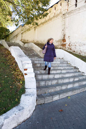 A beautiful young woman is walking down the stairs. The monastery in the city of Vladimir.の写真素材
