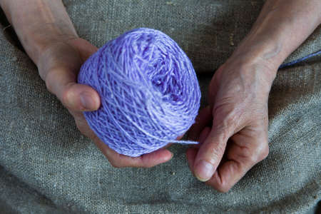A ball of thread in the hands of an elderly woman. Close-up.