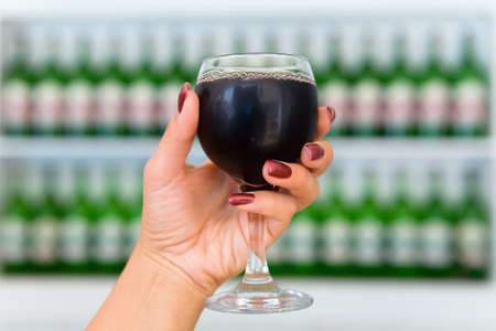 A glass of cool wine in an elegant female hand. The drinks.の写真素材