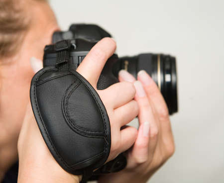 A photo camera with a wrist belt in beautiful female hands. Close-up.の写真素材