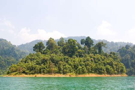 Beautiful desert island covered with wild jungle. Lake Cheo Lan in Thailand.