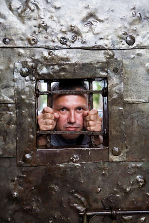 A man looks out from behind the bars. Entrance gate to the Gonio fortress in Georgia.