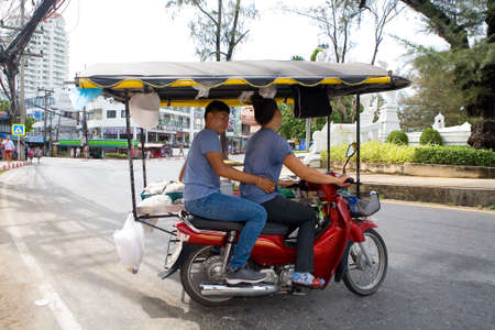 Phuket, Thailand, February 20, 2018: Street vendors of exotic food ride a moped.
