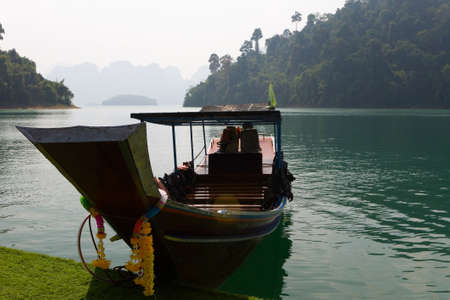 Boat moored to the shore against the backdrop of mountains. Thailand.