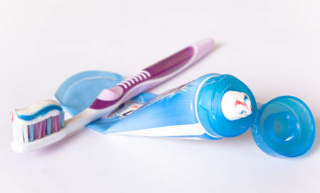 Multi-colored toothpaste on a toothbrush and tube. Close-up.