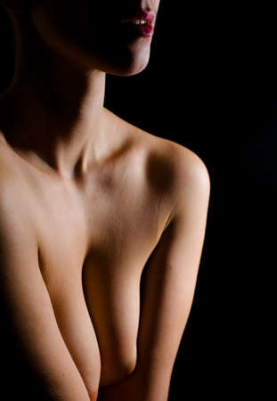 Beautiful nude young adult woman in the dark. Parts of the female body in the nude genre.の写真素材