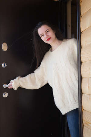 Portrait of a beautiful young brunette girl at the open door. Outdoors.の写真素材